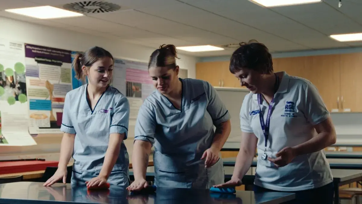 students and staff wearing RGU scrubs experiment with exercise tools