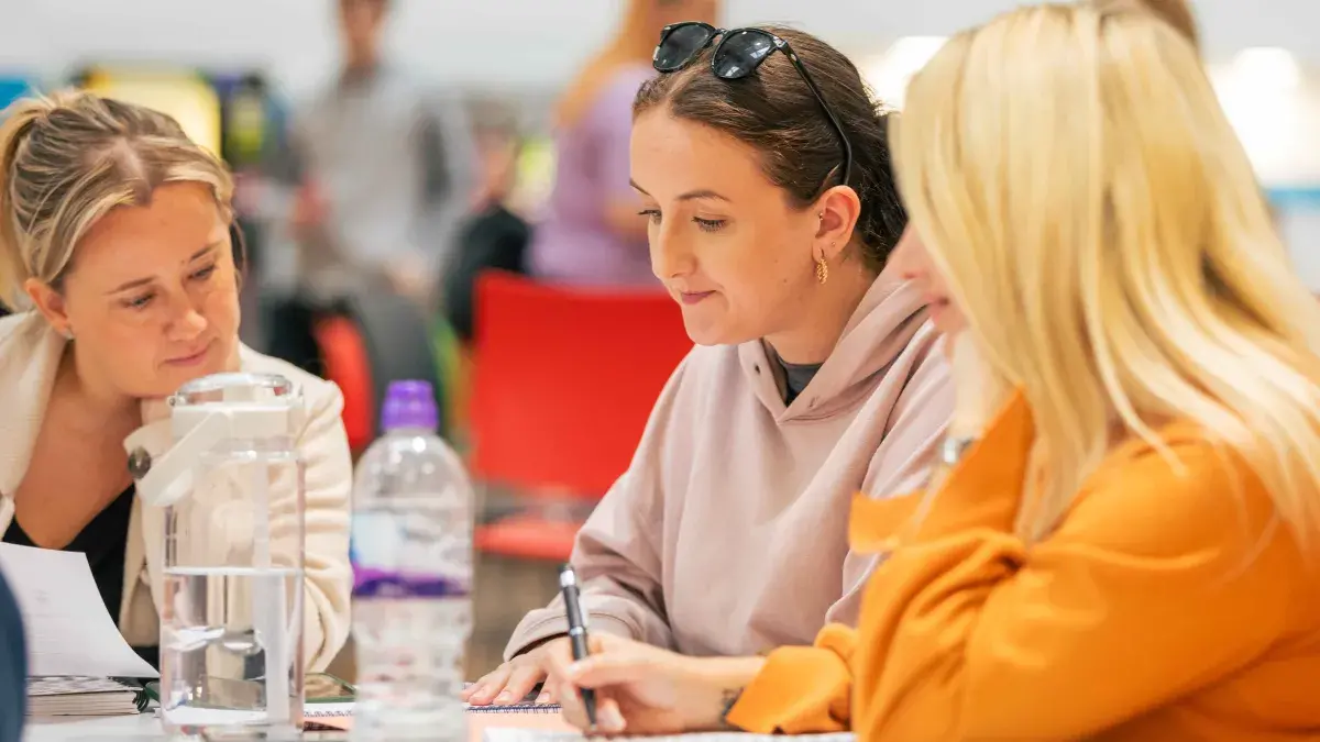 three young women in a college study space work together on their homework