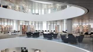 interior of bright, modern library with shelving and chairs over multiple floors