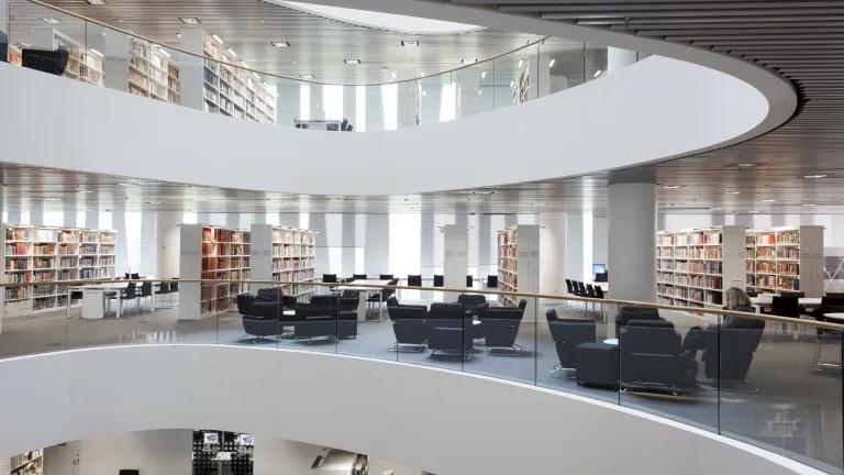 interior of bright, modern library with shelving and chairs over multiple floors
