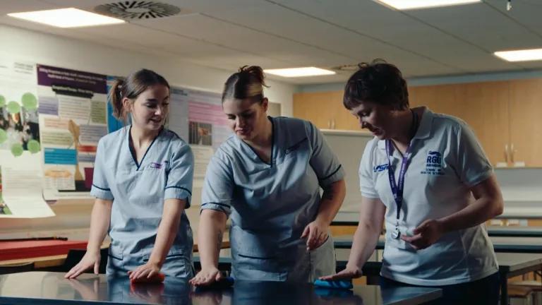 students and staff wearing RGU scrubs experiment with exercise tools
