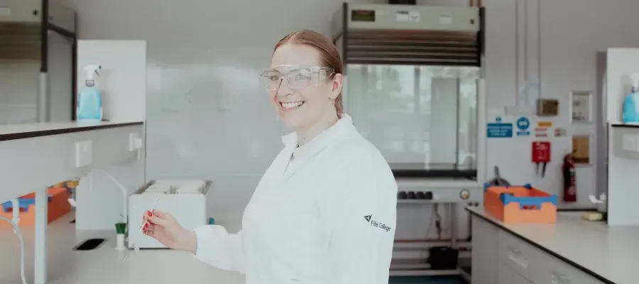 An Access to Health & Life Sciences SWAP student at Fife College smiles at the camera while in a science lab