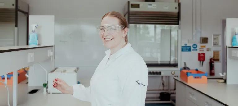 An Access to Health & Life Sciences SWAP student at Fife College smiles at the camera while in a science lab