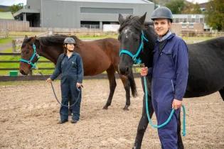 Two former SWAP students pose with horses as part of their Veterinary Medicine studies