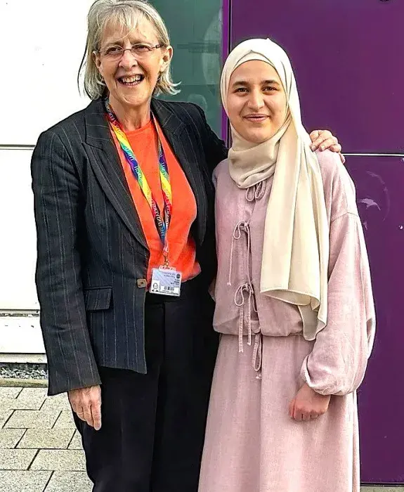 Lesley Dunbar and Batoul pose outside a medical building, smiling and with their arms around each other