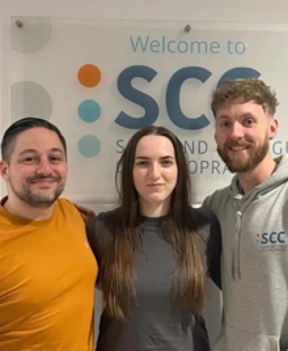 three students pose in front of the SCC sign